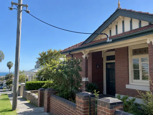 Overhead service cable and bracket on a brick house exterior in Coogee